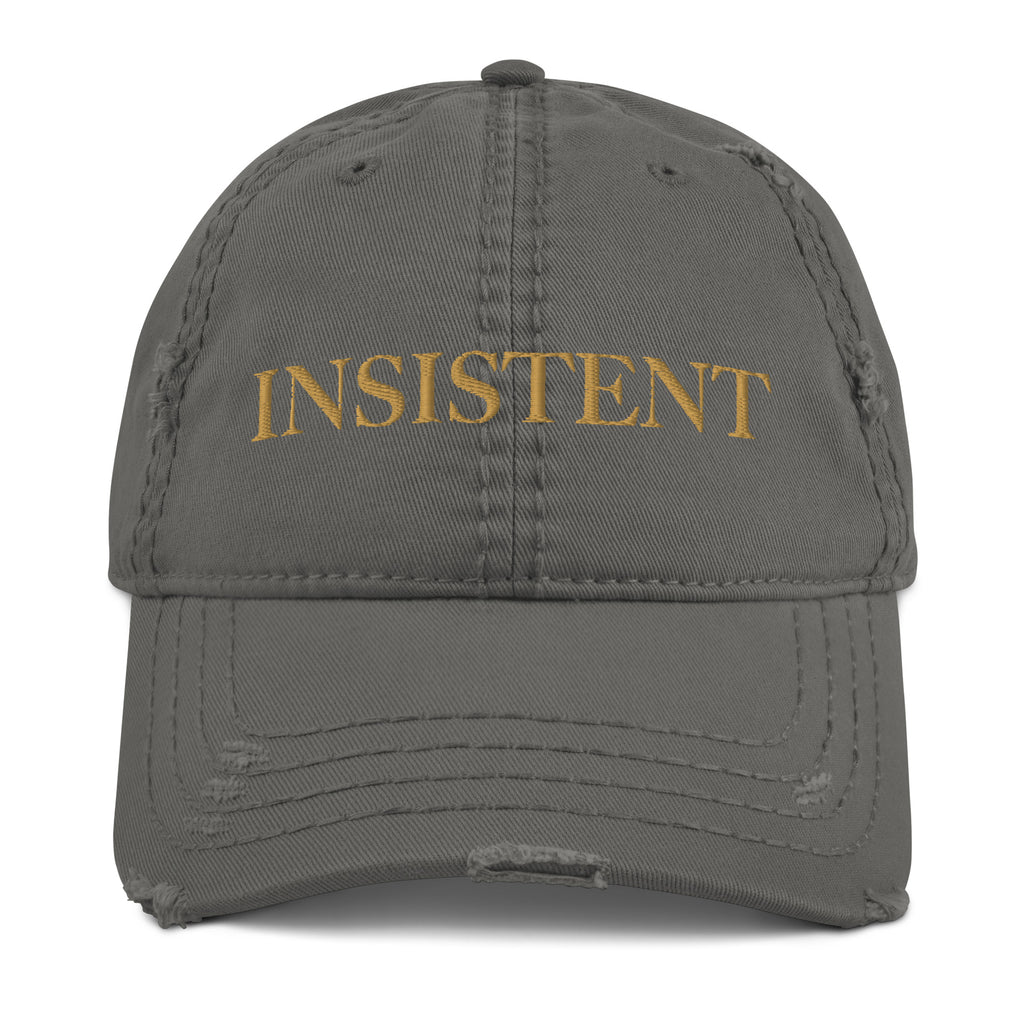 A distressed gray hat with Gold lettering that says, "Insistent."