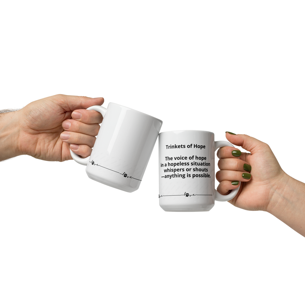 Two hands holding white mugs with text  that says, "Trinkets of Hope. The voice of hope in a hopeless situation whispers or shouts - anything is possible." with a line and a dogs paw around the bottom.on a white background